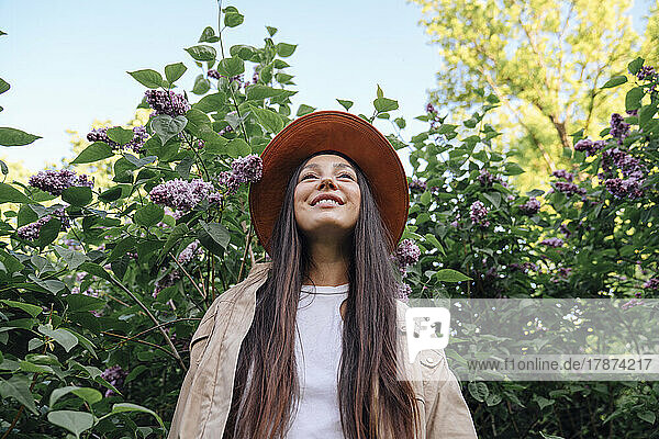 Lächelnde Frau steht neben Blüten im Park