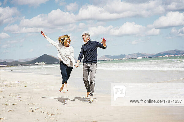 Cheerful mature couple having fun on shore at beach