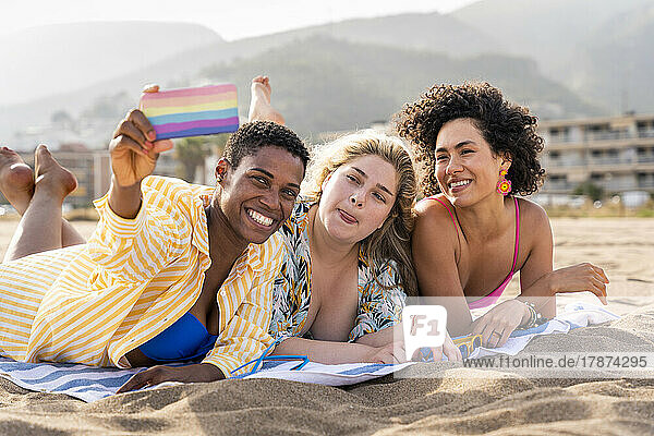 Frau macht Grimasse und macht am Strand ein Selfie mit Freunden auf dem Smartphone