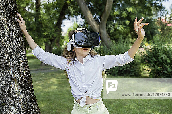 Girl wearing virtual reality simulator standing by tree in park