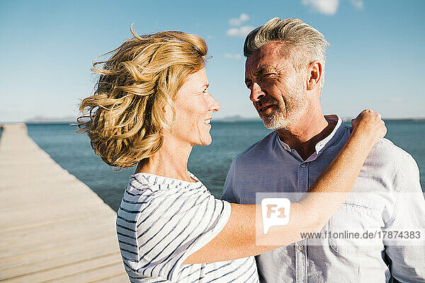 Happy mature couple looking at each other on sunny day