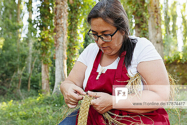 Craftswoman making rope with esparto grass in garden