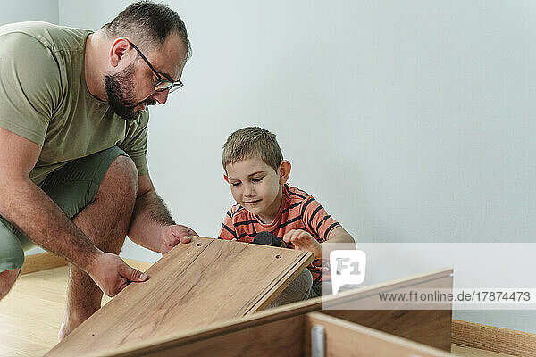 Father and son installing furniture at home