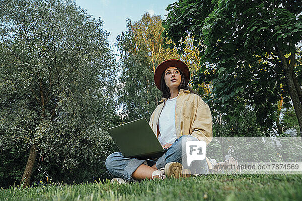 Thoughtful freelancer with laptop in park