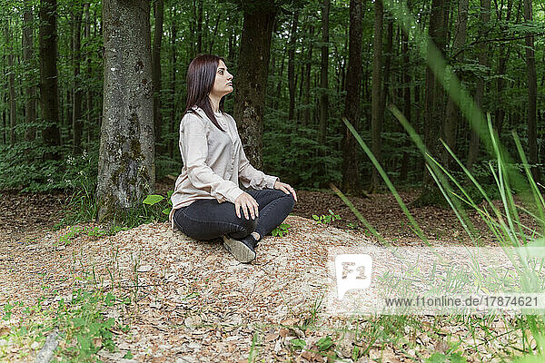 Young woman practicing yoga in forest