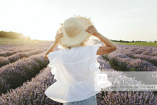 Woman wearing straw hat standing in lavender field