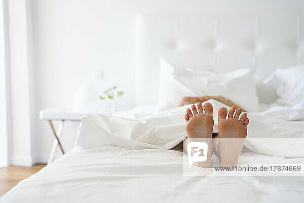 Feet of girl under blanket in bed