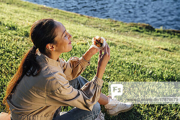 Woman eating lunch on grass in park at sunny day