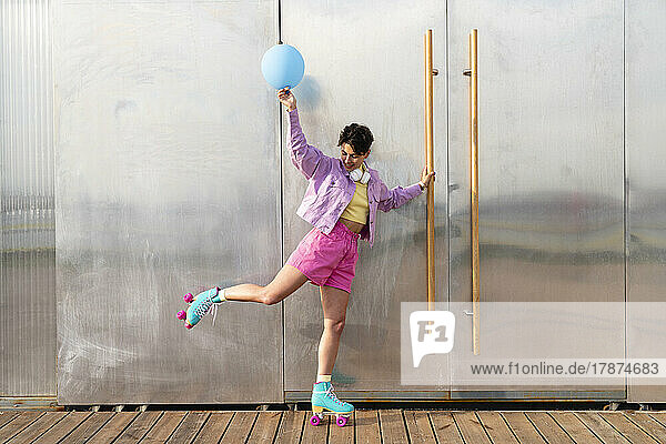 Woman with blue balloon balancing on roller skates by door