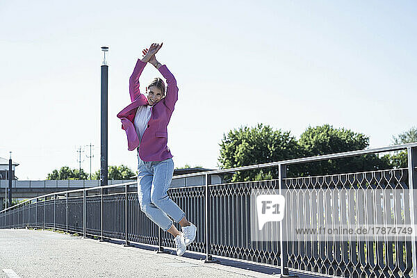 Happy young woman jumping in front of railing