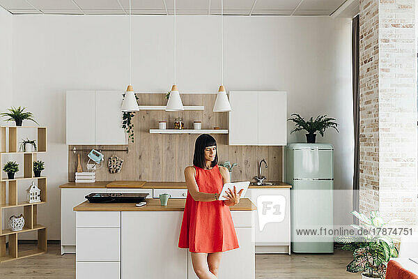 Freelancer woman using tablet PC standing by kitchen island at home