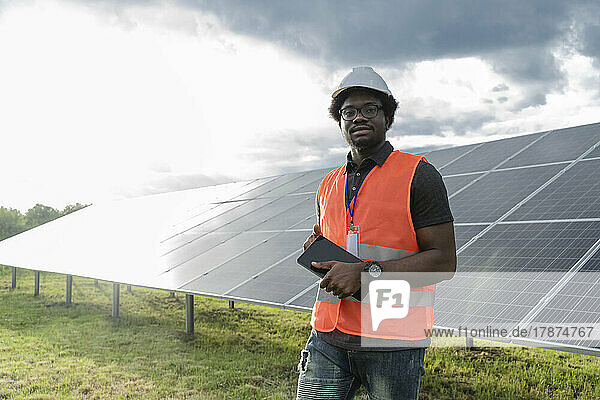 Engineer standing with tablet PC in front of solar panels