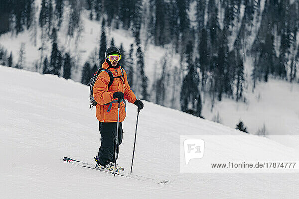 Skifahrer mit Helm und Schutzbrille steht auf Schnee