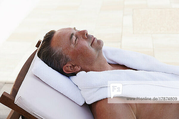 Smiling man relaxing on sun lounger