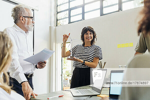 Smiling businesswoman with wind turbine model in meeting at office
