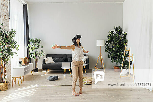Woman using virtual reality simulator in living room at home