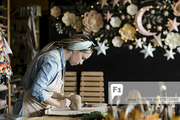 Craftsperson kneading clay on workbench at art studio
