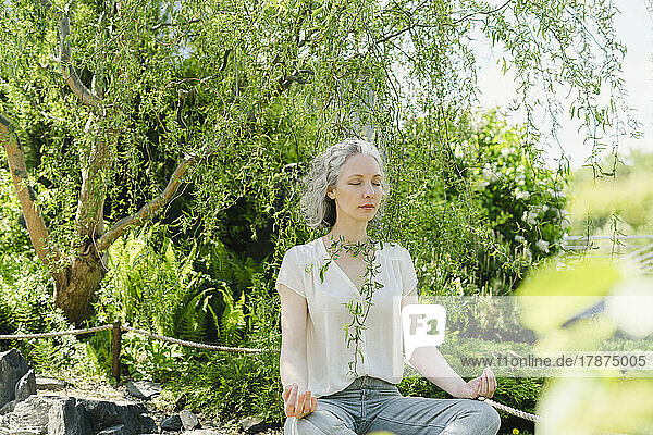 Woman meditating in front of trees at park