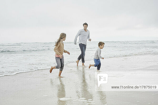 Father running on the beach with son and daughter
