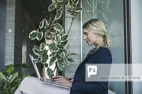Blond businesswoman using laptop sitting in office