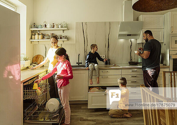 Father and mother with children in kitchen at home