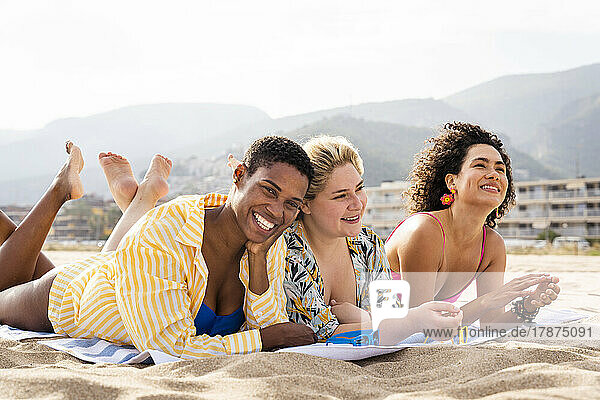 Fröhliche  gemischtrassige Freunde  die sich im Urlaub am Strand hinlegen