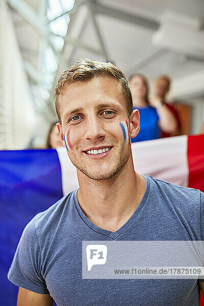 Lächelnder Mann mit französischer Flagge im Gesicht