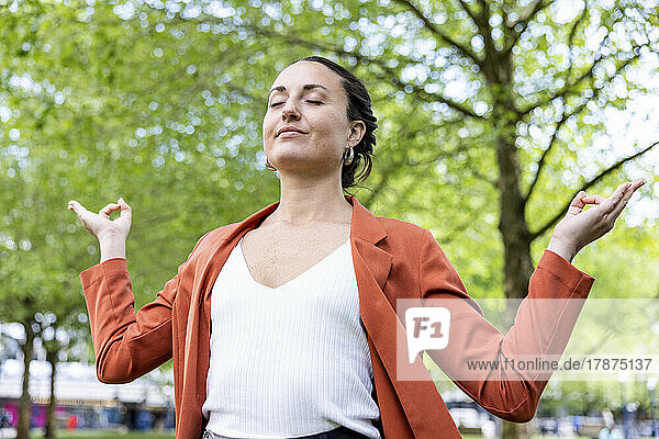 Geschäftsfrau meditiert mit geschlossenen Augen im Park