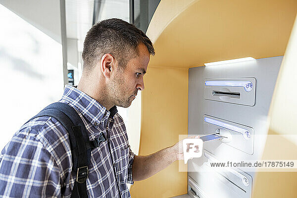 Mature man inserting credit card into ATM machine