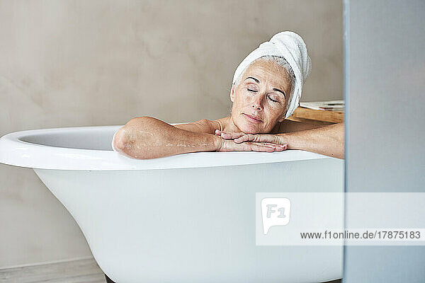 Woman with eyes closed relaxing in bathtub