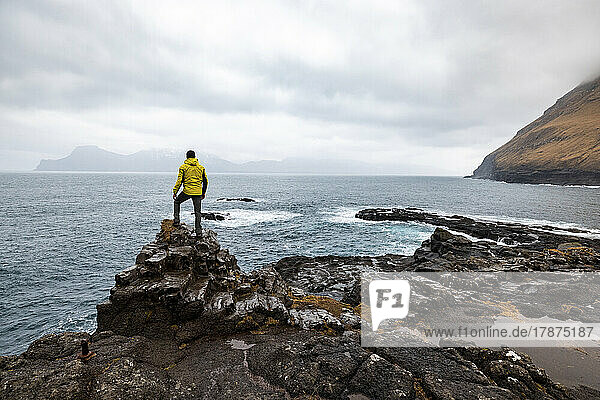 Färöer-Inseln  Eysturoy  Gjogv  männlicher Wanderer  der den Atlantischen Ozean vom Rand einer Klippe aus bewundert