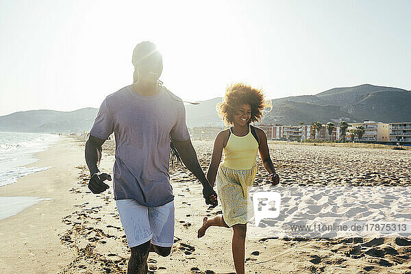 Father and daughter holding hands running at beach