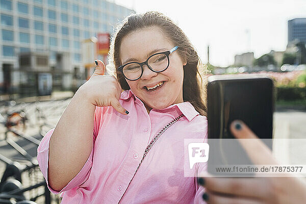 Smiling teenage girl gesturing in front of smart phone