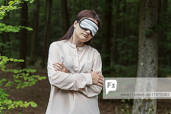 Woman standing with sleeping mask in forest
