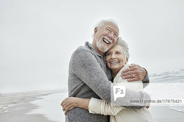 Laughing senior couple embracing at the sea