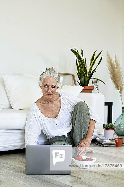 Mature woman using laptop sitting in living room