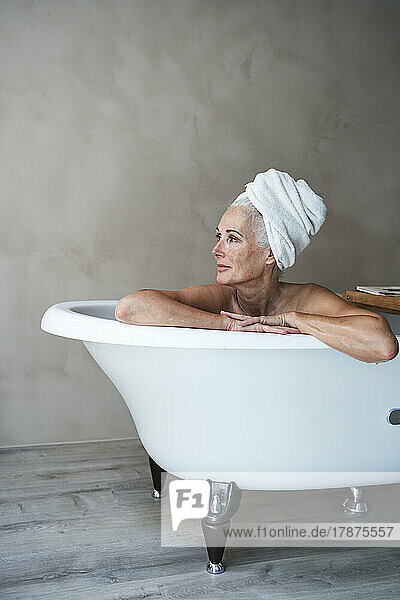 Contemplative woman in bathtub at home