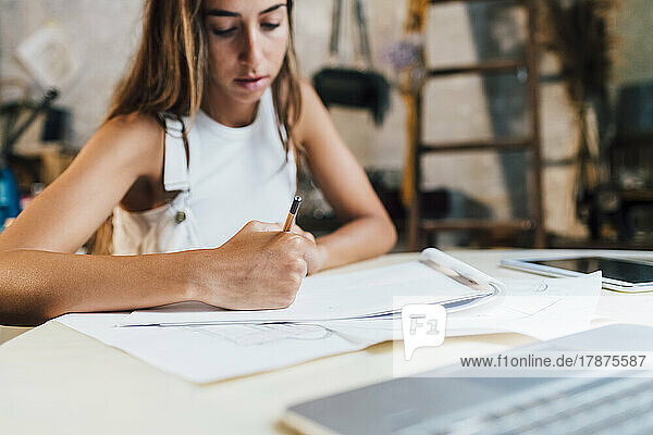 Fashion designer drawing on paper at desk