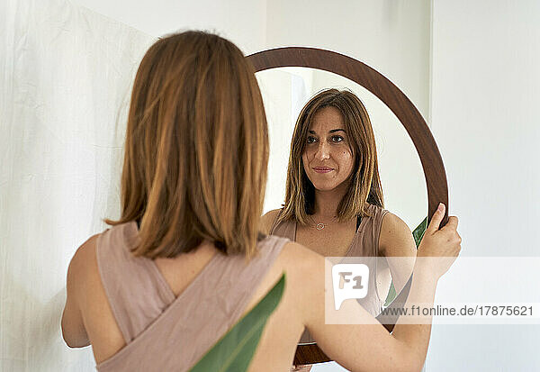 Smiling woman looking in mirror at home