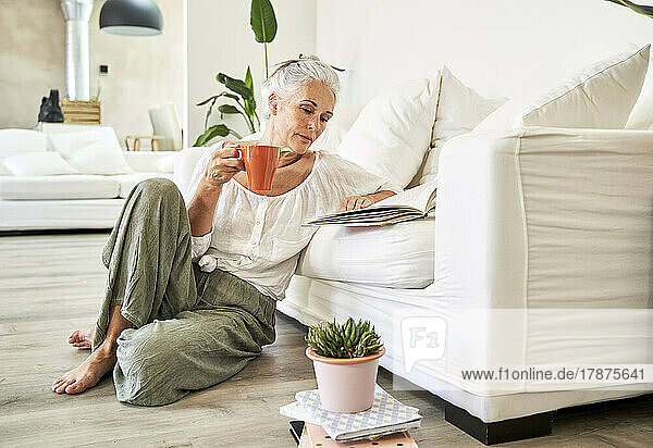 Woman reading book leaning on couch at home