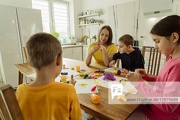 Mother and children playing with kinetic sand at home
