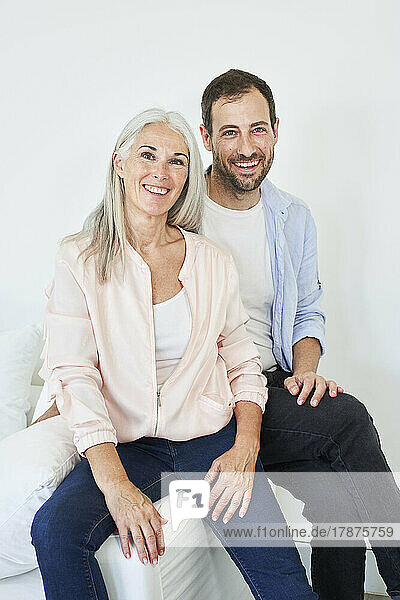 Happy mature woman with son sitting on sofa at home
