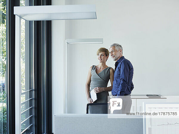 Thoughtful business colleagues looking out through window at office