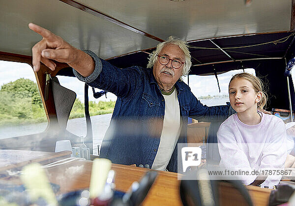 Grandfather pointing by granddaughter in boat