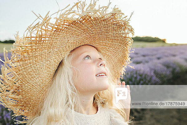 Smiling cute girl wearing hat standing in lavender field