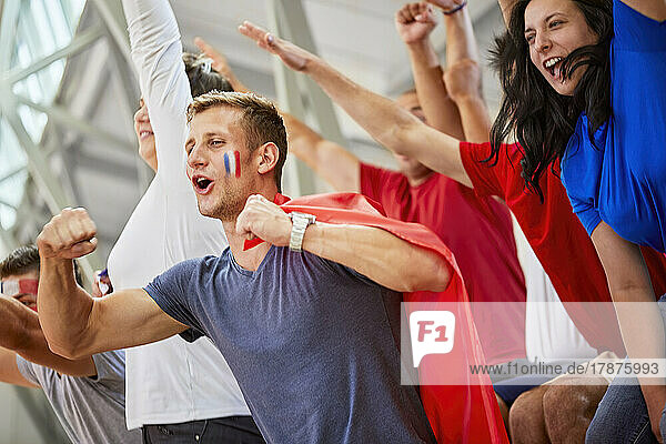 Excited fans cheering together at sports event in stadium