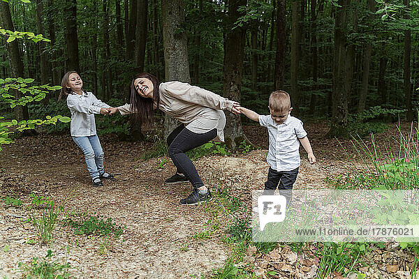 Children pulling mother having fun in forest