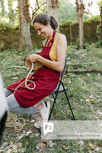 Happy craftswoman weaving esparto grass in garden