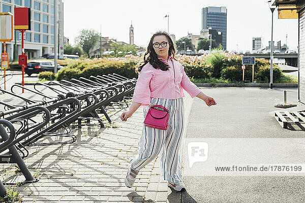 Teenage girl with sling bag puckering on footpath