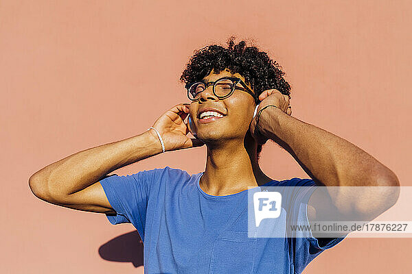 Smiling young man listening music through headphones on sunny day